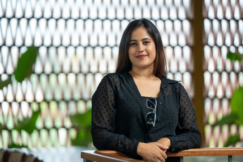 Smiling woman in a casual outfit poses confidently indoors.
